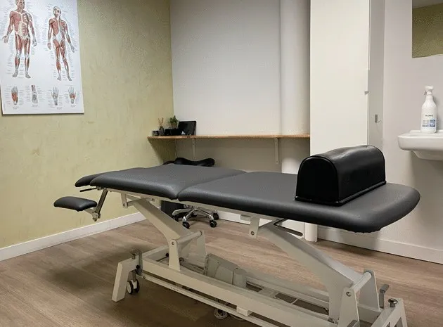 Behandelruimte van BodyFirst met een massagetafel en een anatomieposter